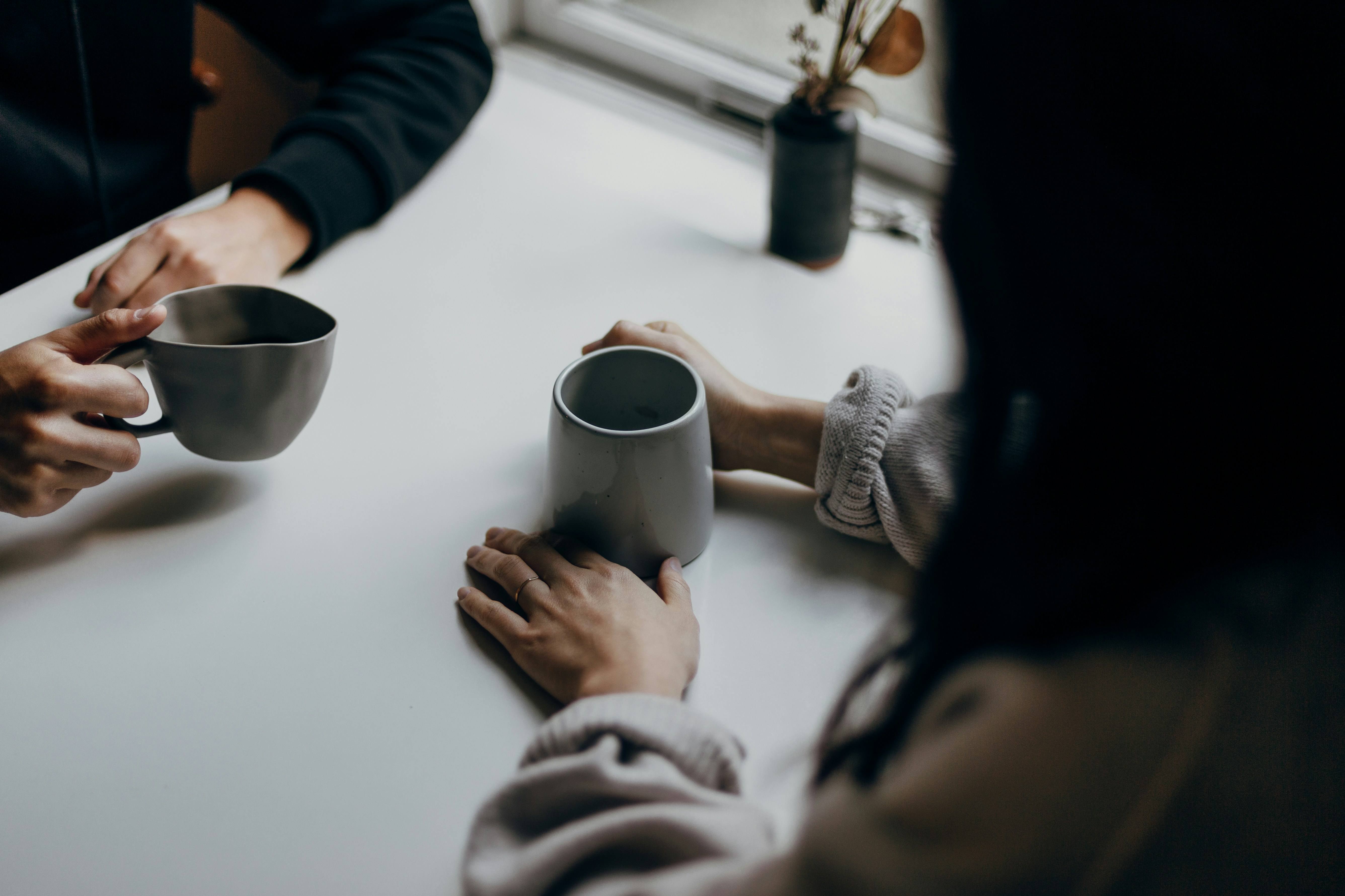 Zwei Personen sitzen zusammen mit Kaffeetassen am Tisch
